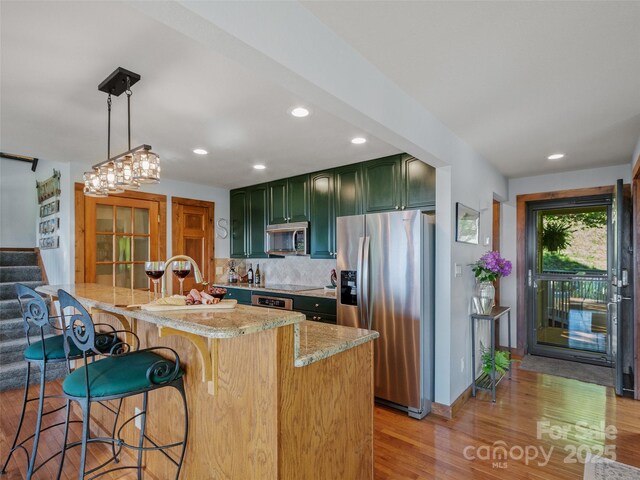 141 Ivy Ridge Rd, Burnsville, NC 28714 - kitchen with appliances with stainless steel finishes, green cabinetry, light wood-type flooring, light stone counters, and tasteful backsplash