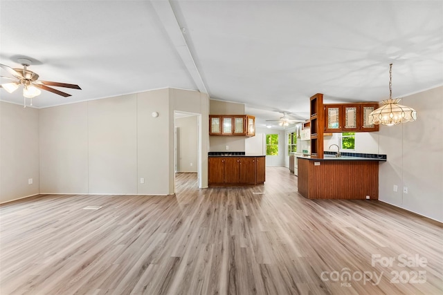 unfurnished living room featuring a sink, vaulted ceiling with beams, ceiling fan with notable chandelier, and light wood-style flooring