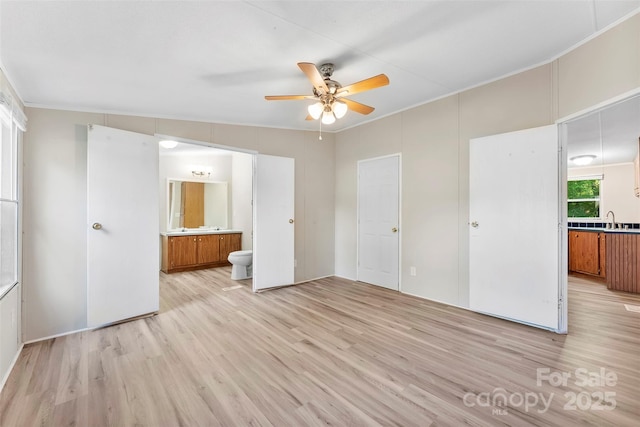 unfurnished bedroom featuring ceiling fan, a sink, ensuite bathroom, light wood-type flooring, and ornamental molding