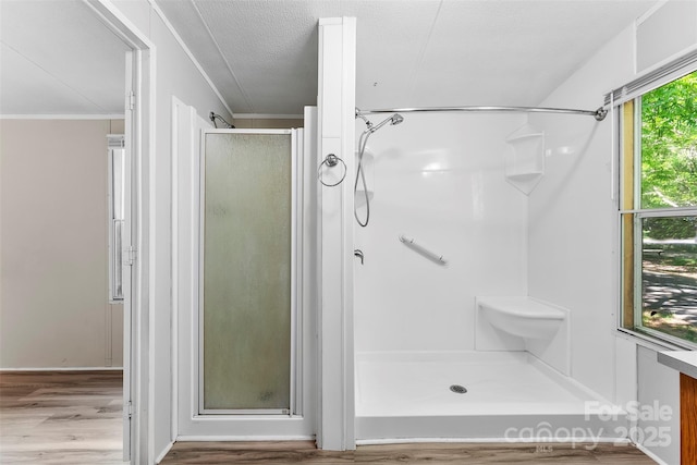 bathroom with ornamental molding, a textured ceiling, wood finished floors, and a shower stall