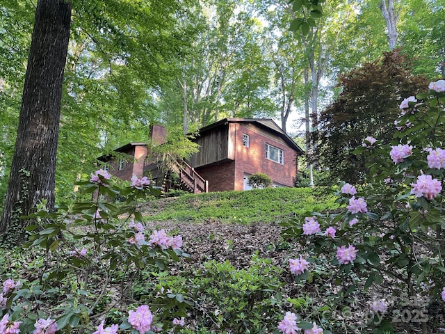 view of side of home with stairs and a chimney
