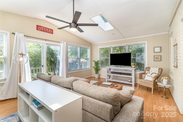 living area with a skylight, lofted ceiling, light wood-style flooring, plenty of natural light, and ceiling fan