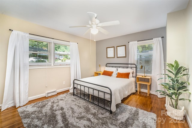 bedroom with multiple windows, wood finished floors, baseboards, and ceiling fan
