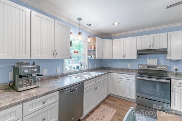kitchen featuring appliances with stainless steel finishes, under cabinet range hood, a sink, light wood-style flooring, and ornamental molding