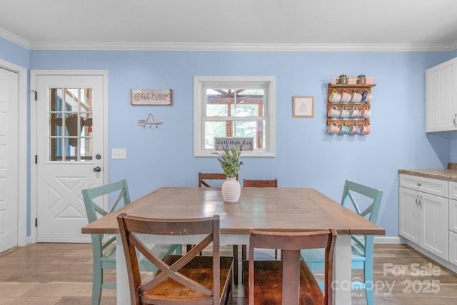 dining area with light wood-style flooring, crown molding, and baseboards