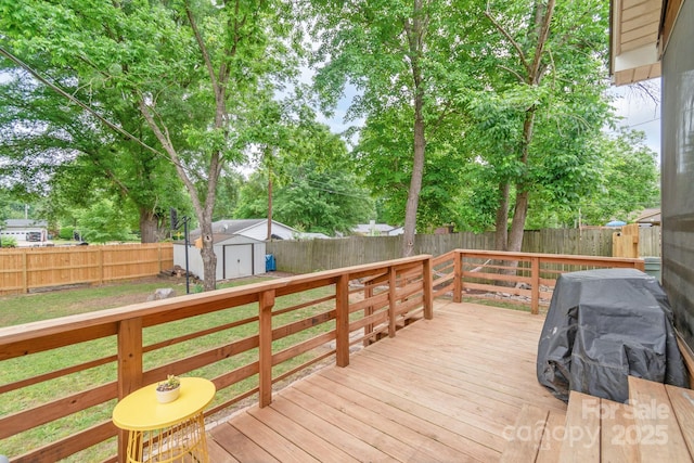 deck featuring a fenced backyard, a storage shed, an outbuilding, and view of scattered trees
