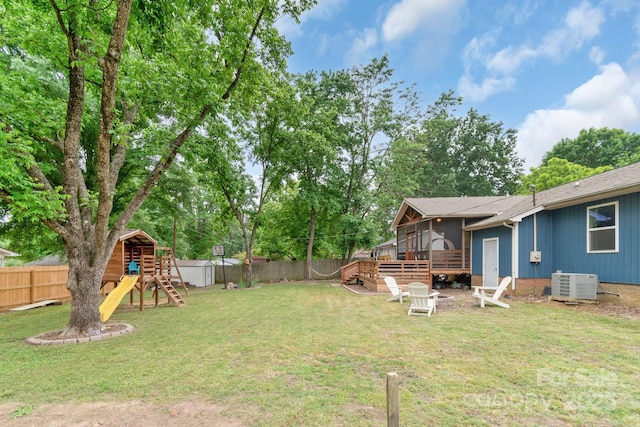 view of yard with a playground, cooling unit, a storage shed, a deck, and an outbuilding