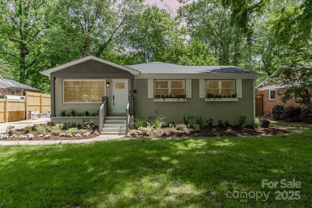 ranch-style house featuring brick siding, a front lawn, and fence