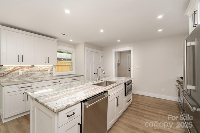 kitchen with a sink, light wood-style floors, stainless steel appliances, recessed lighting, and white cabinetry