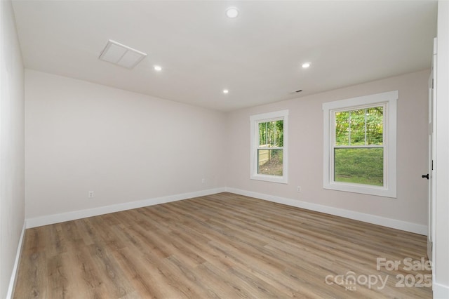 spare room featuring visible vents, light wood-style floors, and baseboards
