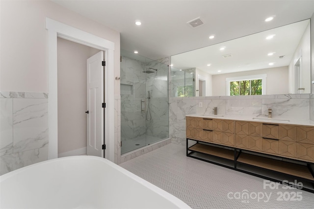 bathroom with visible vents, vanity, a marble finish shower, a soaking tub, and recessed lighting