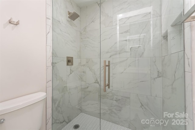 bathroom with a marble finish shower and toilet