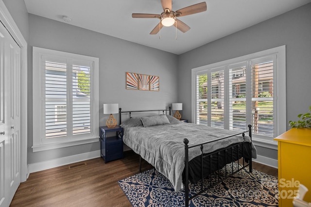 bedroom featuring baseboards, multiple windows, visible vents, and wood finished floors