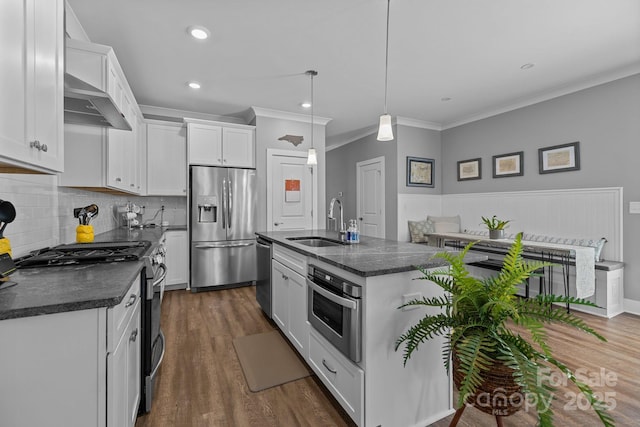 kitchen with a sink, white cabinetry, crown molding, wall chimney exhaust hood, and appliances with stainless steel finishes