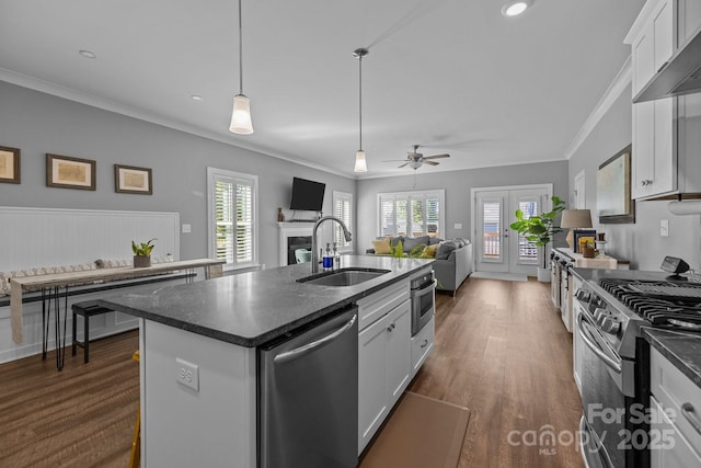 kitchen with a sink, stainless steel appliances, a fireplace, white cabinets, and dark wood-style floors