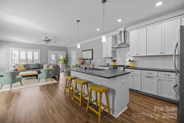 kitchen with a sink, dark countertops, stainless steel appliances, wall chimney range hood, and decorative backsplash