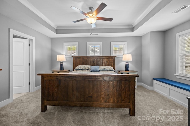bedroom with a tray ceiling, light colored carpet, and visible vents