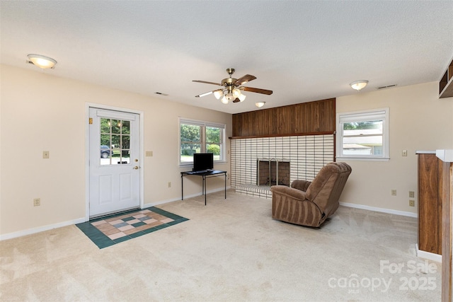 living area featuring ceiling fan, a tile fireplace, and light colored carpet