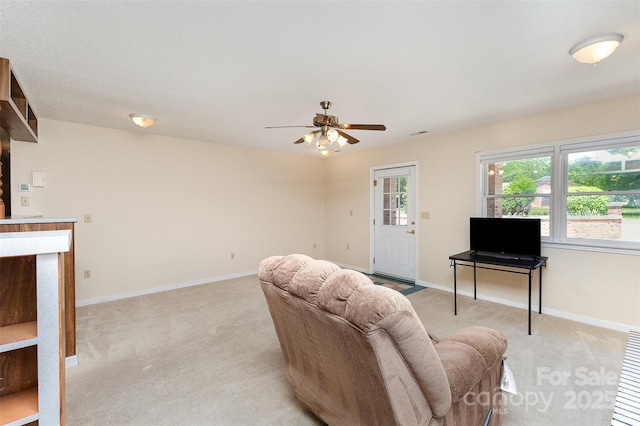 living area with light colored carpet, baseboards, and ceiling fan