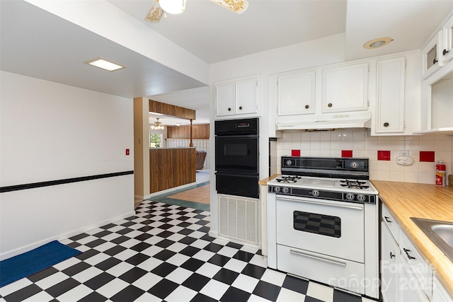 kitchen with black oven, light floors, under cabinet range hood, white cabinets, and white gas range oven