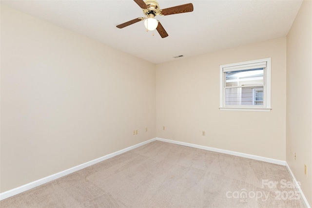 spare room featuring a ceiling fan, baseboards, visible vents, and light carpet