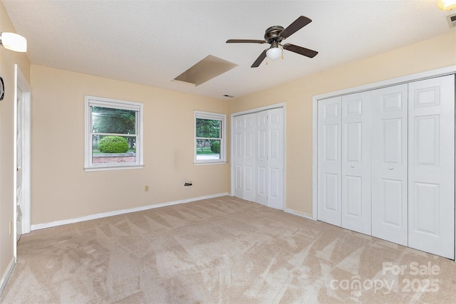 unfurnished bedroom featuring visible vents, baseboards, multiple closets, and carpet