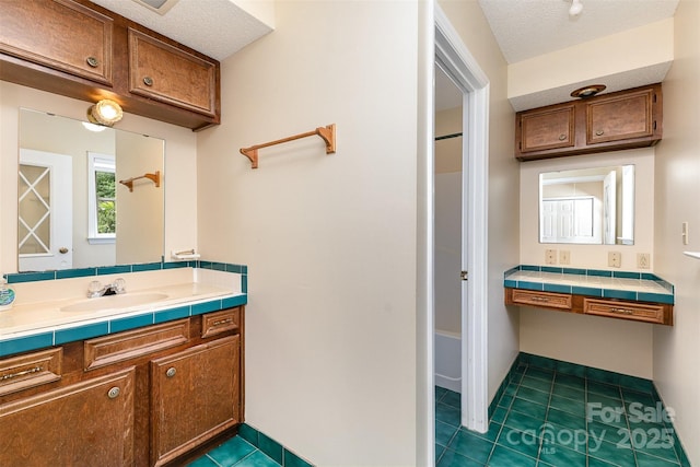 full bathroom featuring a textured ceiling, tile patterned floors, and vanity