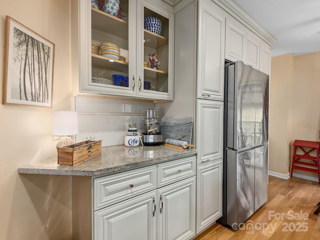 112 Deerlake Dr, Asheville, NC 28803 - kitchen with freestanding refrigerator, tasteful backsplash, light wood-type flooring, glass insert cabinets, and light stone countertops