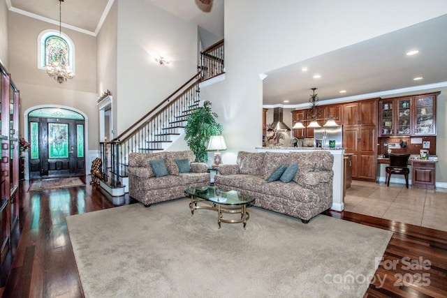 112 Eagle Chase Ln, Troutman, NC 28166 - living area featuring ornamental molding, stairs, a chandelier, a towering ceiling, and wood finished floors