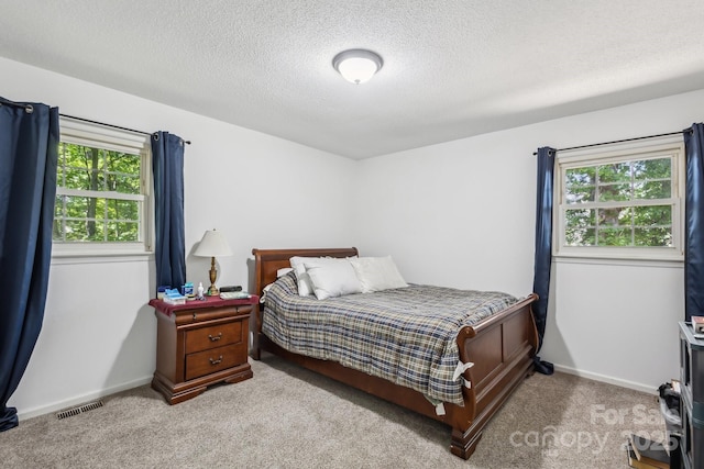 bedroom with visible vents, carpet flooring, a textured ceiling, and baseboards
