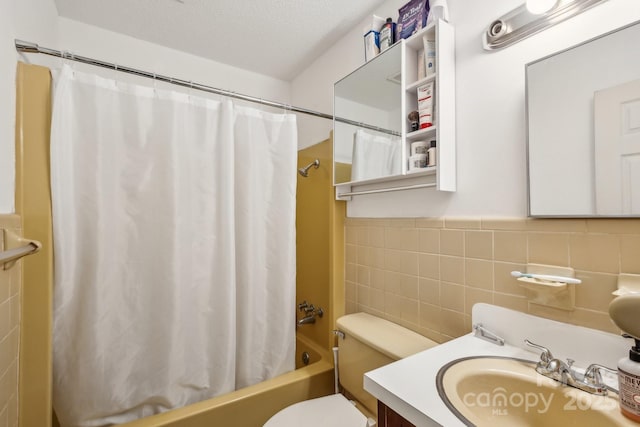 bathroom with a textured ceiling, tile walls, shower / tub combo, vanity, and toilet