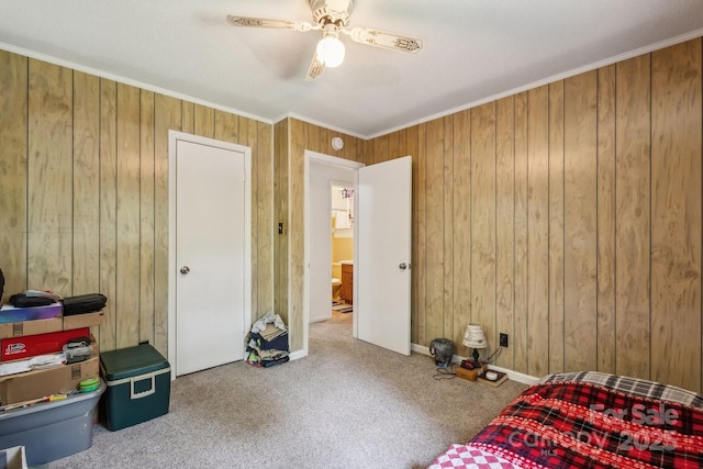 unfurnished bedroom with wooden walls, carpet floors, ornamental molding, and a ceiling fan