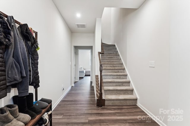 stairs with baseboards, visible vents, and wood finished floors