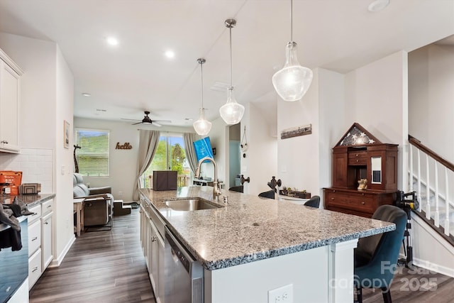 kitchen with stainless steel dishwasher, dark wood-style floors, a kitchen island with sink, and a sink