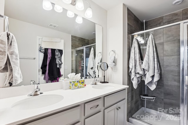 bathroom with a shower stall, visible vents, a sink, and double vanity