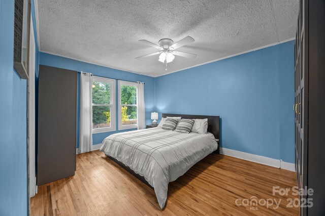 1001 Old Charlotte Rd, Concord, NC 28027 - bedroom with a textured ceiling, wood finished floors, baseboards, and a ceiling fan