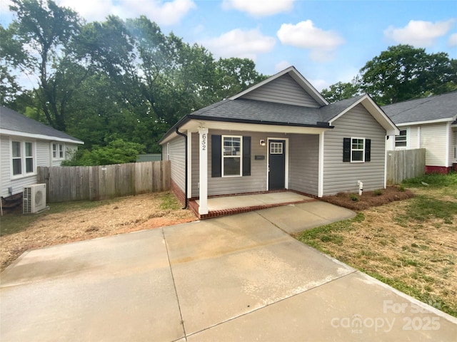bungalow featuring a shingled roof, ac unit, fence, and covered porch