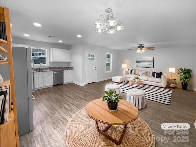 living room with a healthy amount of sunlight, ceiling fan with notable chandelier, and light wood-style floors