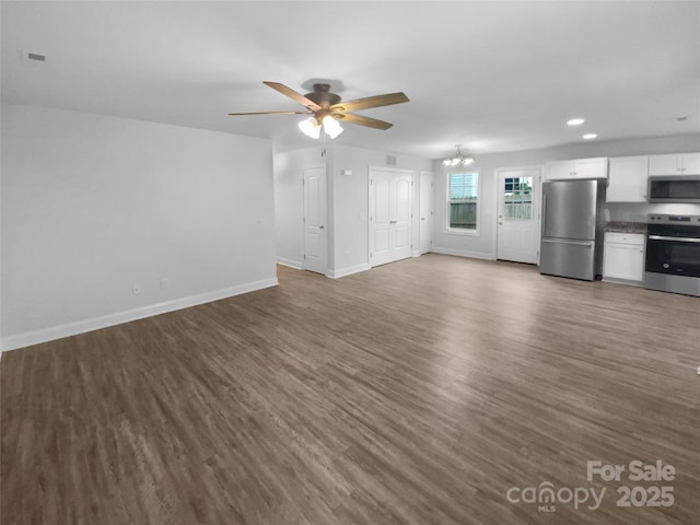 unfurnished living room featuring recessed lighting, baseboards, ceiling fan with notable chandelier, and dark wood-style flooring