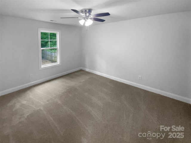 carpeted spare room with baseboards, a ceiling fan, and visible vents