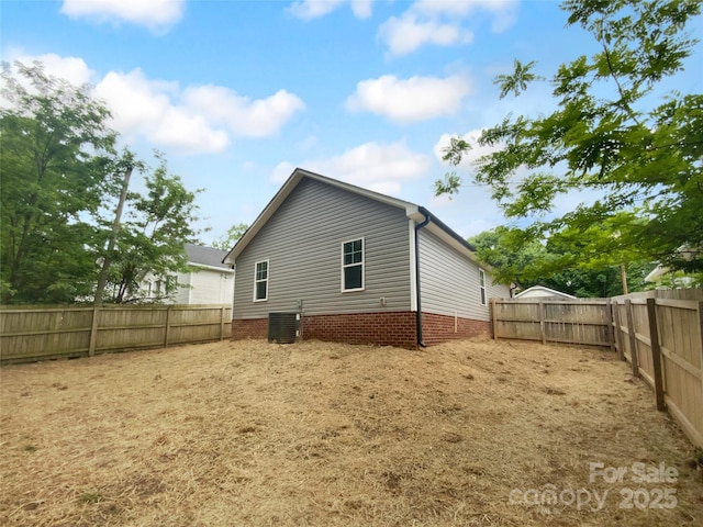 rear view of property with a fenced backyard and central AC unit