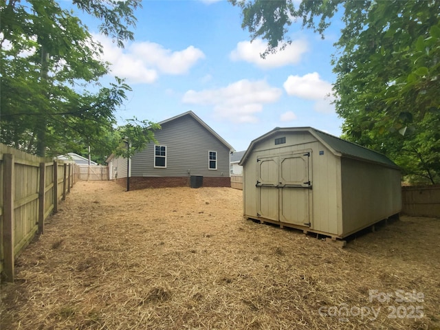 rear view of house with a storage shed, an outdoor structure, and a fenced backyard