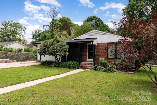 view of front facade with fence, brick siding, a garage, a front yard, and driveway