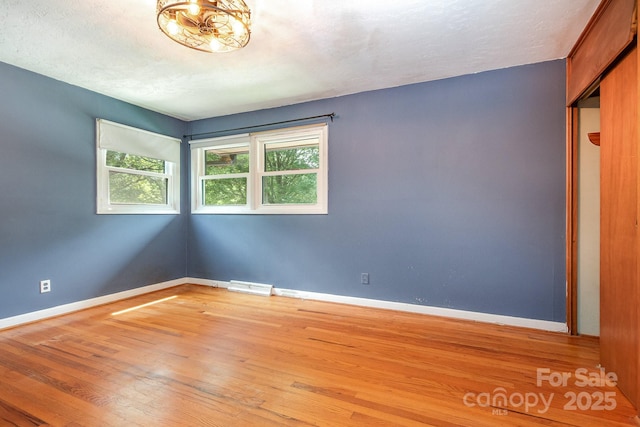 spare room with light wood-type flooring, baseboards, and visible vents