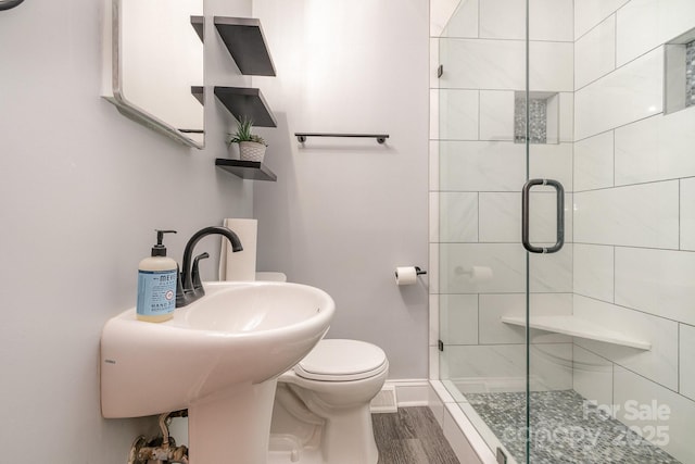 full bath with toilet, baseboards, wood finished floors, and a stall shower