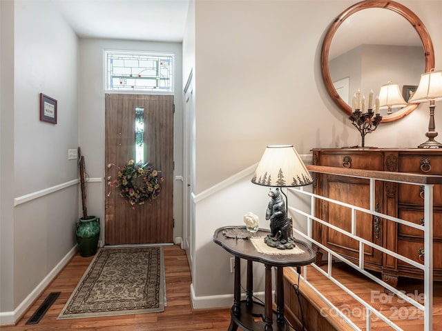 foyer entrance featuring baseboards, wood finished floors, and visible vents