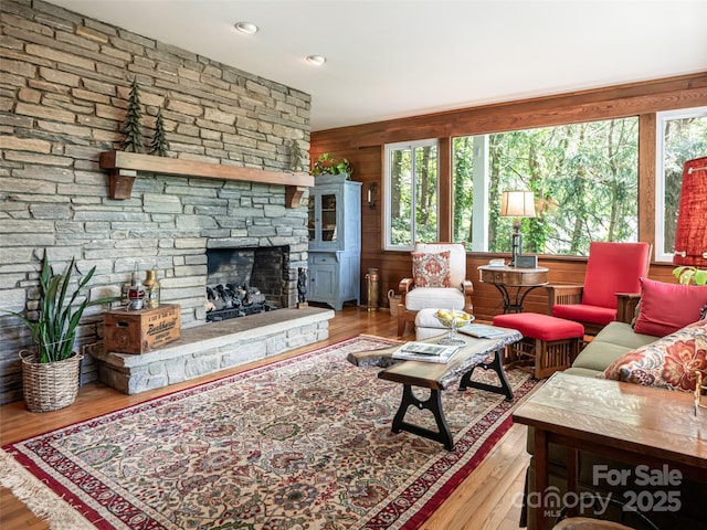 living room featuring plenty of natural light, a fireplace, wood walls, and wood finished floors