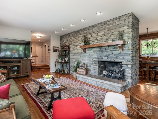 living area with a stone fireplace and wood finished floors
