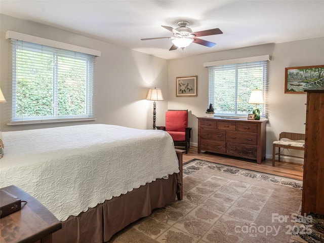 bedroom featuring multiple windows, a ceiling fan, and wood finished floors