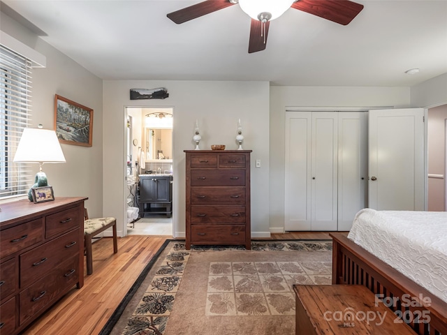 bedroom featuring light wood-style floors, a ceiling fan, a closet, and ensuite bath